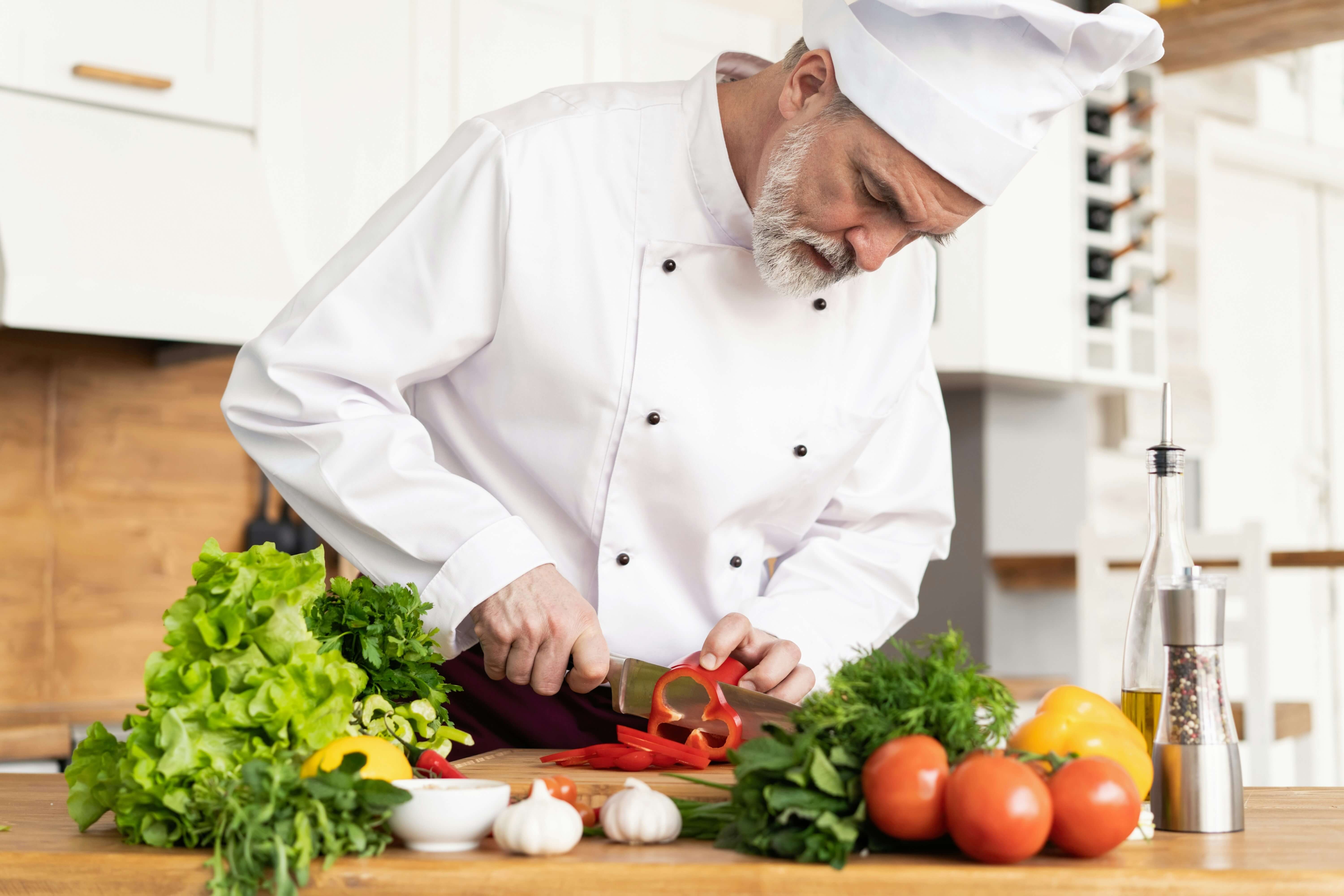 A chef cutting vegetables in a restaurant kitchen